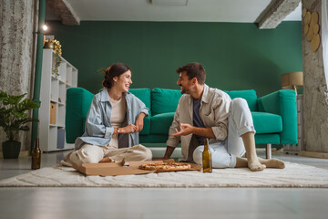 Happy couple enjoying pizza and beer at home