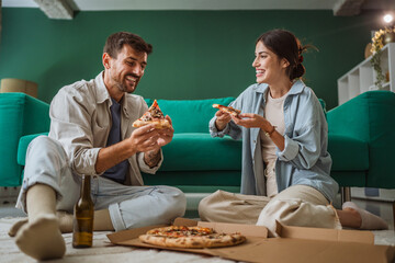 Happy couple enjoying pizza together at home