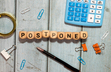 Postponed - words from wooden blocks with letters, postponed concept, top view gray background.
