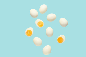 Flying many boiled chicken eggs on blue background