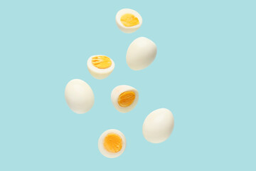 Flying boiled chicken eggs on blue background