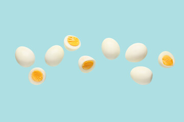 Flying many boiled chicken eggs on blue background