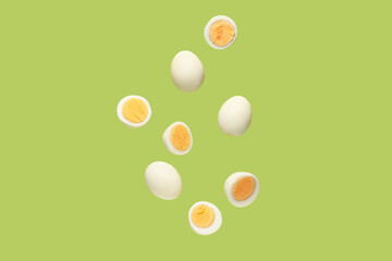 Flying many boiled chicken eggs on green background