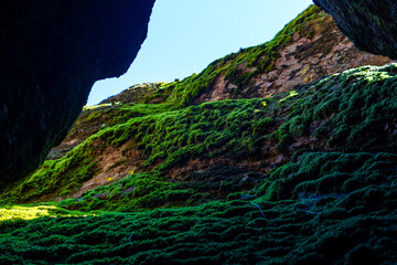A beam of light cuts through the darkness, illuminating the rocky, narrow passages of a talus cave...