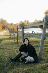 a portrait of a brunette girl dressed in a light dress and a knitted sweater walking in the countryside