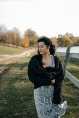a very natural and elegant woman poses for a photo against the backdrop of nature, dressed in light...
