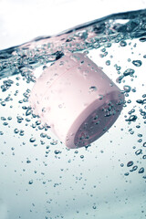 Pink cosmetic jar underwater with air bubbles