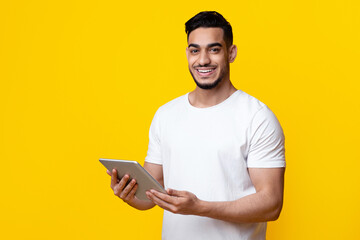 Cheerful arab guy with brand new digital tablet, panorama with copy space, yellow studio...