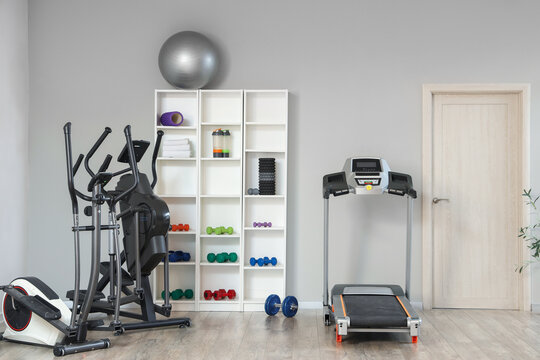Interior of gym with shelf unit, sports equipment and door - Powered by Adobe