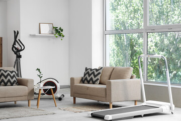 Interior of living room with sofas, elliptical machine and treadmill