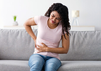 Health care, illness, pain in abdomen, side and back. Sad unhappy young african american sick...