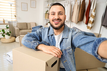 Young man with wardrobe box taking selfie in dressing room