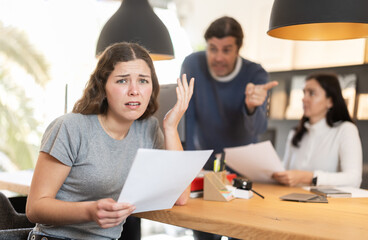 Obraz premium Upset girl argues with store managers, unhappy with terms of purchase agreement in a furniture store