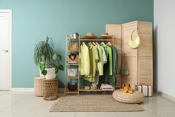 Interior of dressing room with clothes rack, folding screen and plants