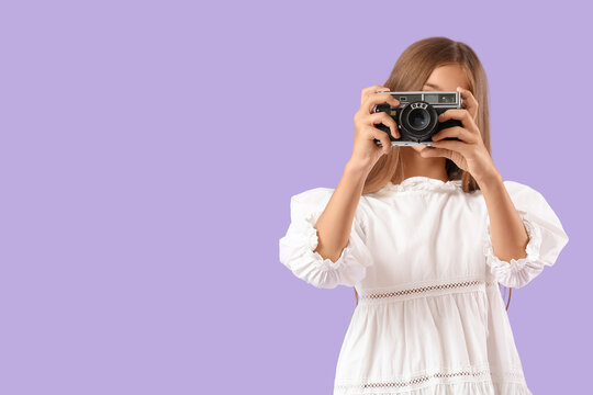 Teenage girl with photo camera on lilac background