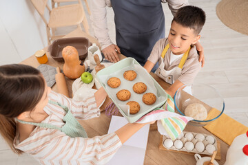 Father and his children with tasty cookies in kitchen