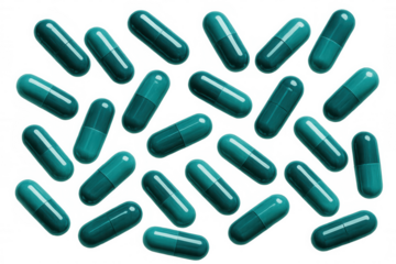 Teal green pharmaceutical capsules scattered across transparent surface, representing medical healthcare design element