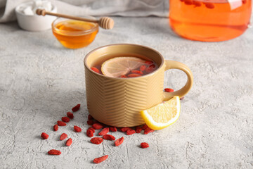 Cup of hot goji tea with lemon and glass bowl of honey on white background