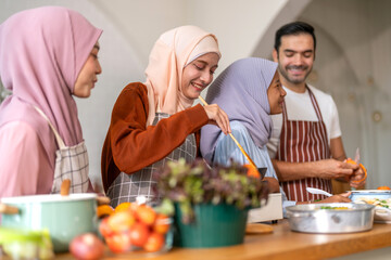 Muslim family cooking together in kitchen preparing food with fresh vegetables, islamic holiday...