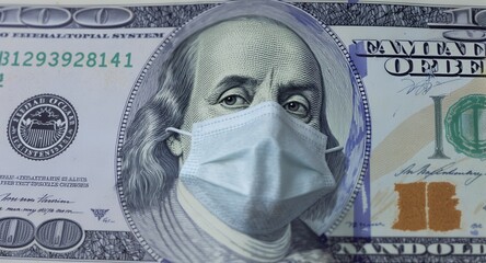 Close-up of a hundred dollar bill with a face mask on the portrait