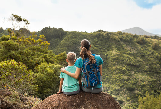 Mother and son enjoy a vibrant view during a hiking adventure in green hills. The bonding experience outdoor activities, showing happiness, exploration, and family unity 
