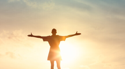 silhouette of a woman standing with open arms, embracing the warmth and light of the sun, evoking a sense of , praise, worship, freedom, positivity, and joyful connection with nature and self