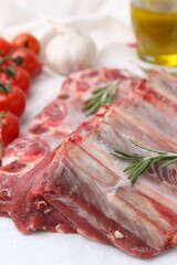 Fresh raw beef ribs, tomatoes and spices on table, closeup