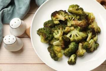 Tasty fried broccoli and shakers on light wooden table, flat lay