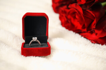 Dreams come true. Beautiful engagement ring in box and flowers on light plaid, closeup