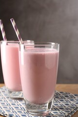 Tasty milkshakes in glasses on wooden table, closeup
