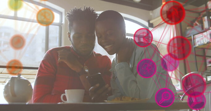 Couple wearing red shirt and denim jacket checking smartphone at cafe, with digital network graphic