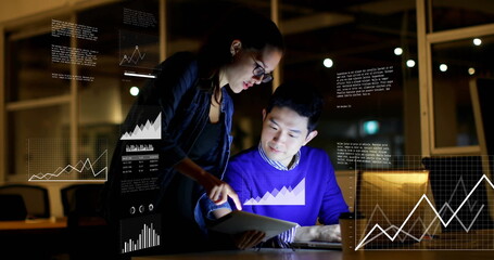 Analyzing data man and woman wearing business attire reviewing tablet and laptop in office at night