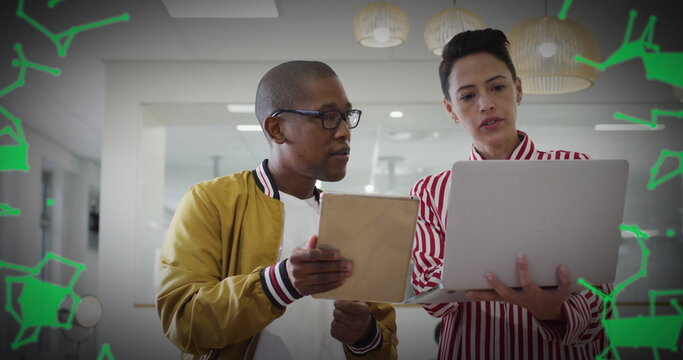 Reviewing content on tablet, laptop in open office by bomber-jacketed man and striped-blouse woman - Powered by Adobe