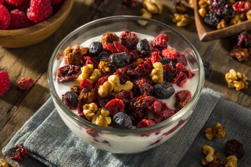 Delicious yogurt topped with granola and mixed berries on a rustic wooden table