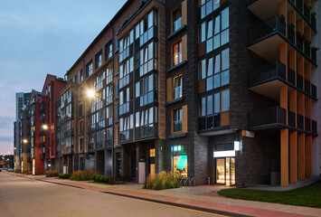 Fototapeta premium New modern block of flats in green area at night. residential apartment with flat buildings exterior. luxury house complex. Part of City Real estate property, condo architecture. apartment