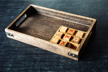 Wooden tic-tac-toe game on dark surface, showcasing handcrafted design and playful strategy.