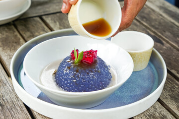 Kuih Sagu Melaka Bunga Telang, a traditional Malaysian dessert made with blue butterfly pea-infused tapioca pearls, served with palm sugar syrup and coconut milk.