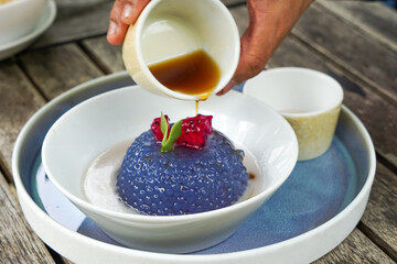 Kuih Sagu Melaka Bunga Telang, a traditional Malaysian dessert made with blue butterfly pea-infused tapioca pearls, served with palm sugar syrup and coconut milk.