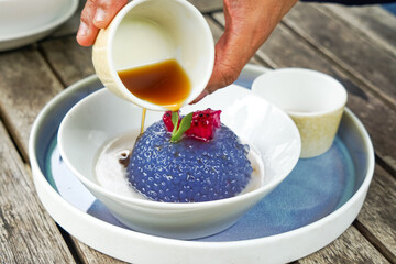 Kuih Sagu Melaka Bunga Telang, a traditional Malaysian dessert made with blue butterfly pea-infused tapioca pearls, served with palm sugar syrup and coconut milk.
