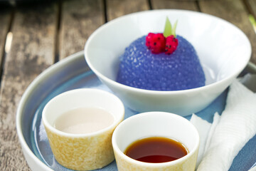 Kuih Sagu Melaka Bunga Telang, a traditional Malaysian dessert made with blue butterfly pea-infused tapioca pearls, served with palm sugar syrup and coconut milk.