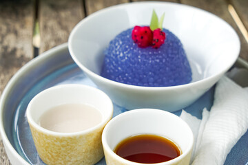 Kuih Sagu Melaka Bunga Telang, a traditional Malaysian dessert made with blue butterfly pea-infused tapioca pearls, served with palm sugar syrup and coconut milk.