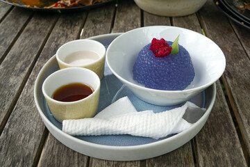 Kuih Sagu Melaka Bunga Telang, a traditional Malaysian dessert made with blue butterfly pea-infused tapioca pearls, served with palm sugar syrup and coconut milk.