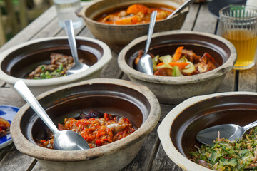 A flavorful assortment of side dishes served with rice, including spicy red snapper in tamarind gravy, crispy fried chicken, stir-fried chili eggplant, rich beef rendang, and seasoned vegetable salad.