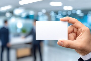 Hand holding blank business card in modern office