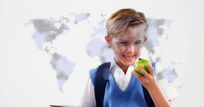 School-age boy holding books examining apple with education map appearing raising apple forward