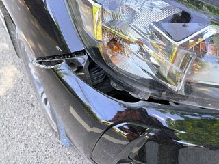 A close-up view shows the black car's damaged and dented bumper on the front due to a traffic...