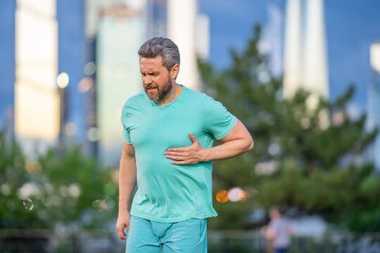Fit man suffering chest pain during workout. Runner feeling heart attack symptoms. Handsome male in heart attack pain outdoors. Cardio exercise an heart attack. Painful moment of heart infarction.