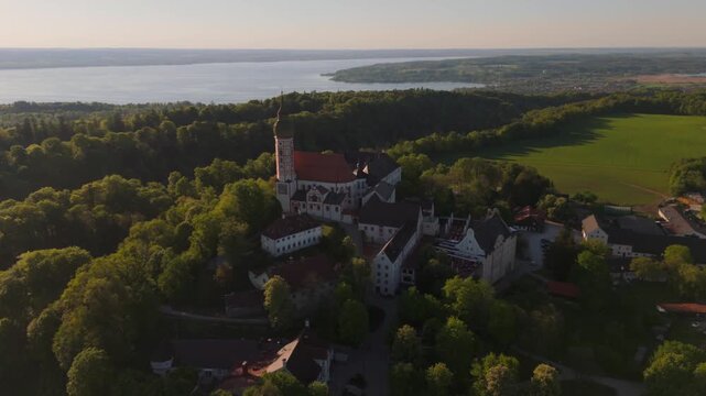 Aerial drone video of Kloster Andechs and pilgrimage church on Holy Mountain by Lake Ammersee, Bavaria, Germany. Scenic sunset view of monastery, nature, and rural landscape near Munich