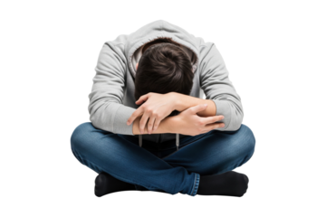 Sad and depressed young man in a hoodie hiding his face in his arms.