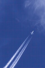 Jet plane trails across deep blue sky